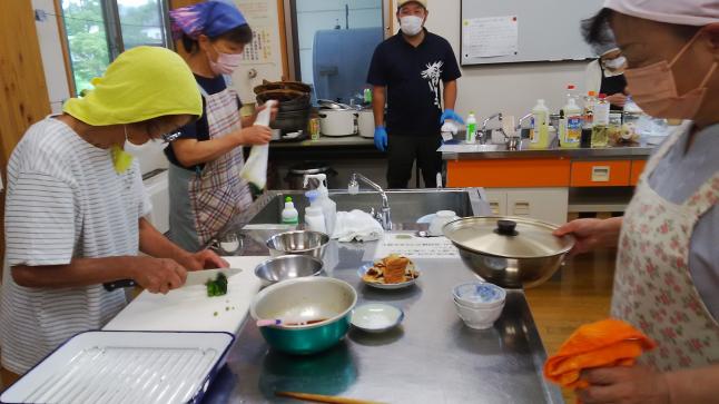菅さんの息子さんが見守る中、料理に励む委員